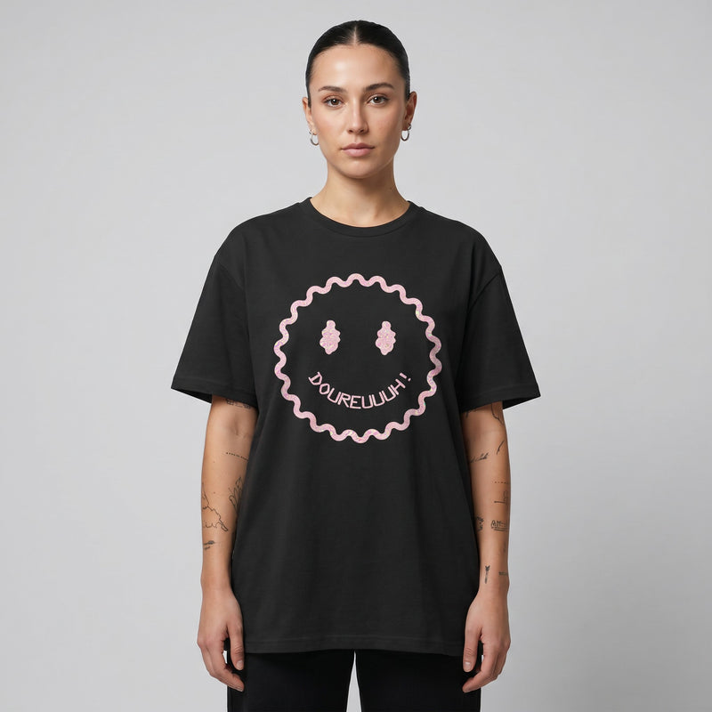 T-shirt Dour Festival DOUREUUUH oversize noir porté par un homme, smiley acid holographique, studio