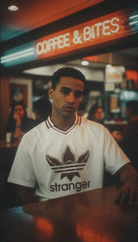T-shirt oversized stranger porté devant une enseigne lumineuse - col V rouge et blanc