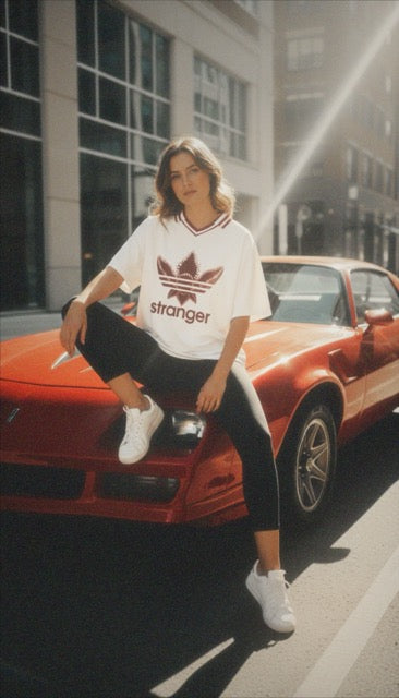 T-shirt blanc inspiré de Stranger Things porté devant des façades colorées et une voiture jaune
