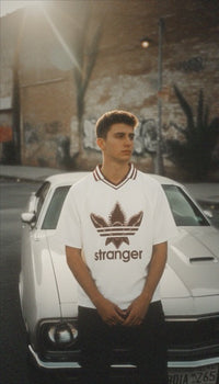 T-shirt oversized inspiré de Stranger Things porté devant une voiture blanche vintage