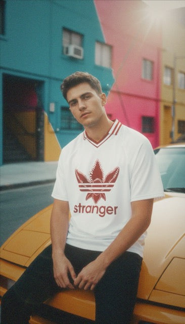 T-shirt oversized stranger porté sur une voiture orange dans une ruelle ensoleillée