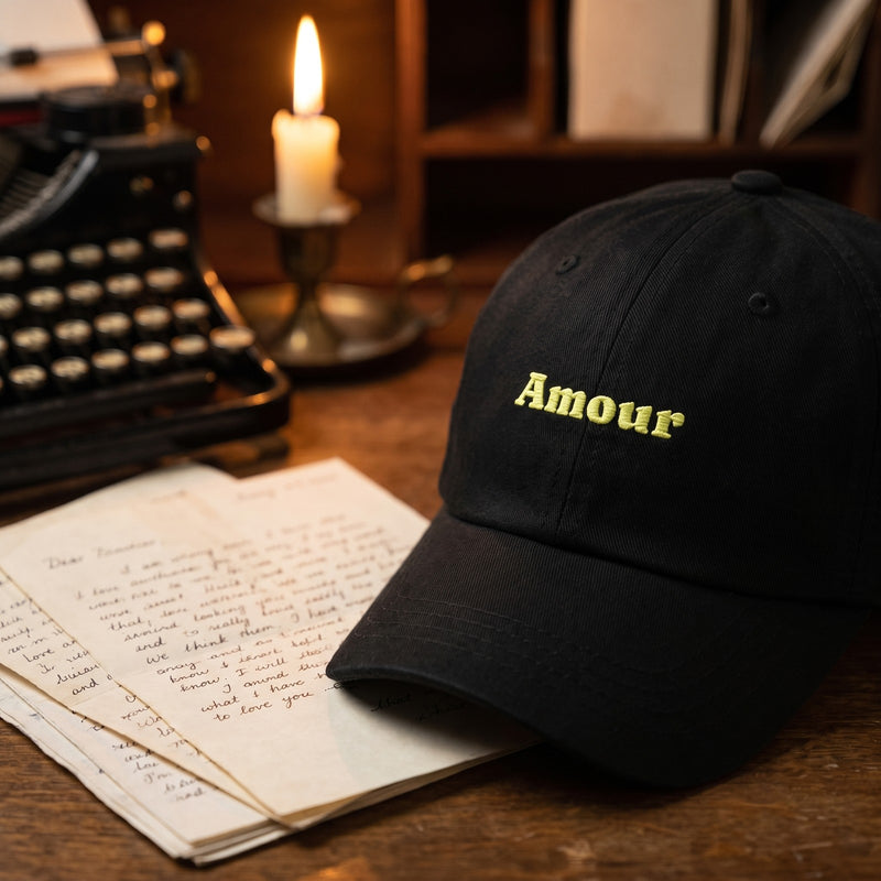 Casquette dad hat noire brodée Amour posée sur un bureau d'écrivain avec des lettres d'amour et une machine à écrire - CHT'M Boutique