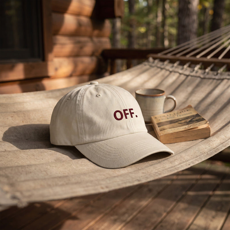 Casquette baseball oyster brodée OFF. en bordeaux foncé posée sur un hamac sur le porche d'une cabane à côté d'un livre et d'un mug, lumière ensoleillée paresseuse - CHT'M Boutique