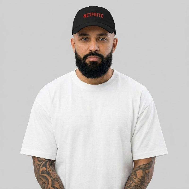 Homme barbu tatoué portant la casquette belge NETFRITE, dad hat noire brodée rouge – photo studio