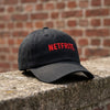 Casquette originale NETFRITE noire posée sur un muret – vue trois quarts, visière courbée