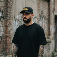 Homme portant la casquette belge noire Flexfit, mot BELGE brodé fil doré, streetwear à Bruxelles