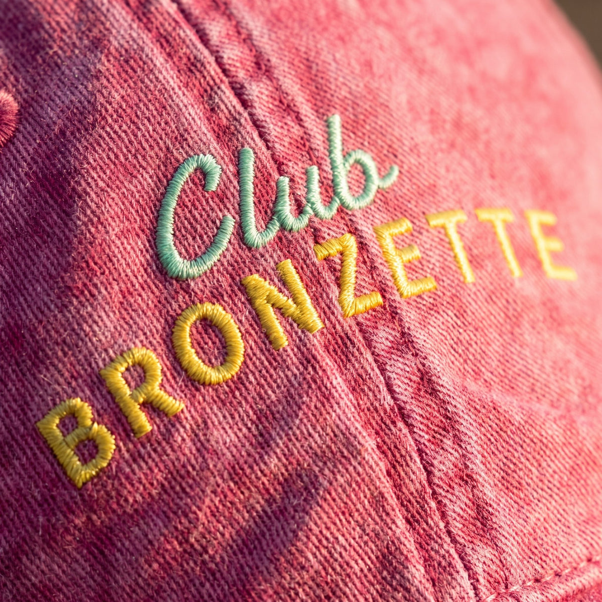 Macro de la broderie Club Bronzette fil vert menthe et jaune sur sergé de coton rose délavé
