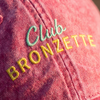 Macro de la broderie Club Bronzette fil vert menthe et jaune sur sergé de coton rose délavé
