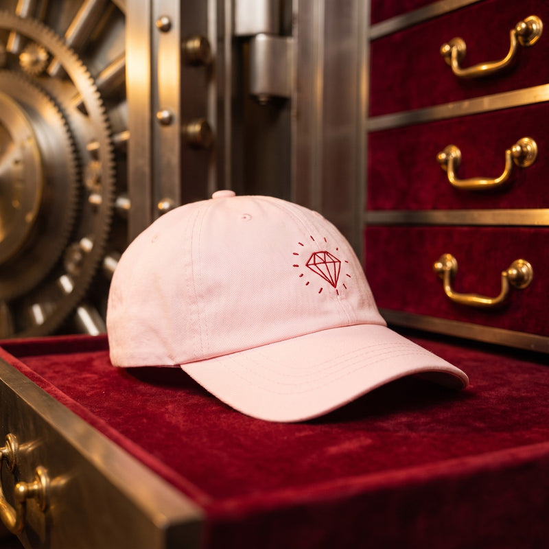 Casquette rose pastel brodée Diamond rouge posée dans un coffre-fort ouvert avec des tiroirs en velours - CHT'M Boutique