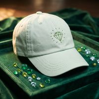 Casquette vert pastel brodée Diamond posée sur un plateau de bijoutier en velours avec des pierres précieuses - CHT'M Boutique