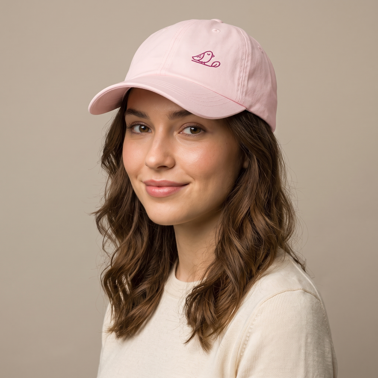 Femme portant la casquette femme rose pastel brodée d'un oiseau, studio