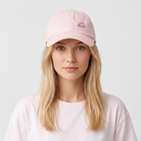 Femme blonde portant la casquette femme rose pastel brodée oiseau, fond clair