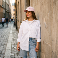 Casquette femme rose pastel portée en look streetwear, ruelle pavée