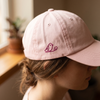 Détail de la broderie oiseau sur la casquette rose pastel portée