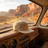 Casquette five panel posée sur le tableau de bord d'un van vintage en road trip dans le désert