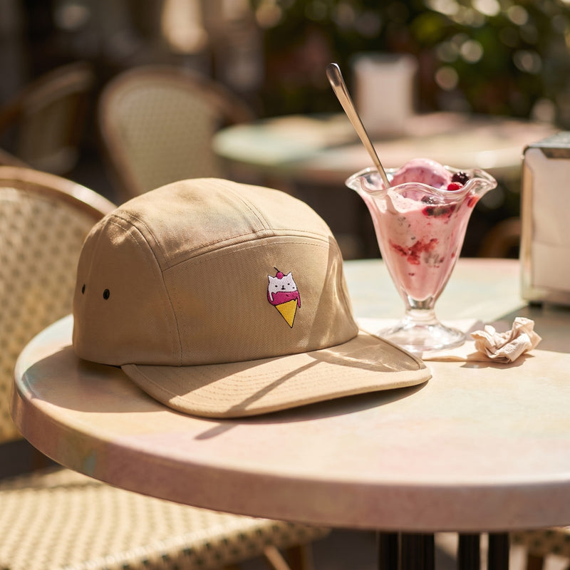 Casquette 5 panneaux kaki brodée d'une glace à tête de chat posée sur une table de café pastel à côté d'une coupe de glace en plein été - CHT'M Boutique