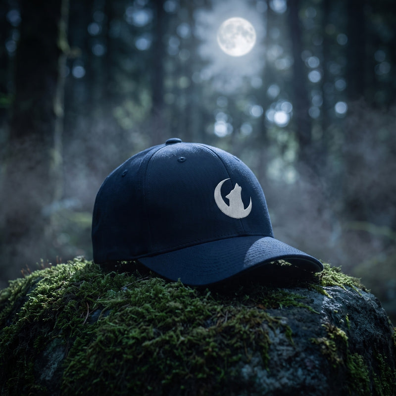 Casquette Flexfit fermée à l'arrière bleu marine brodée d'un loup hurlant à la lune en blanc posée sur un rocher couvert de mousse dans une forêt de nuit sous la pleine lune avec de la brume - CHT'M Boutique