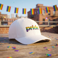 Casquette Flexfit fermée à l'arrière blanche brodée pride aux couleurs arc-en-ciel posée sur une terrasse de toit ensoleillée avec des fanions arc-en-ciel et des confettis - CHT'M Boutique