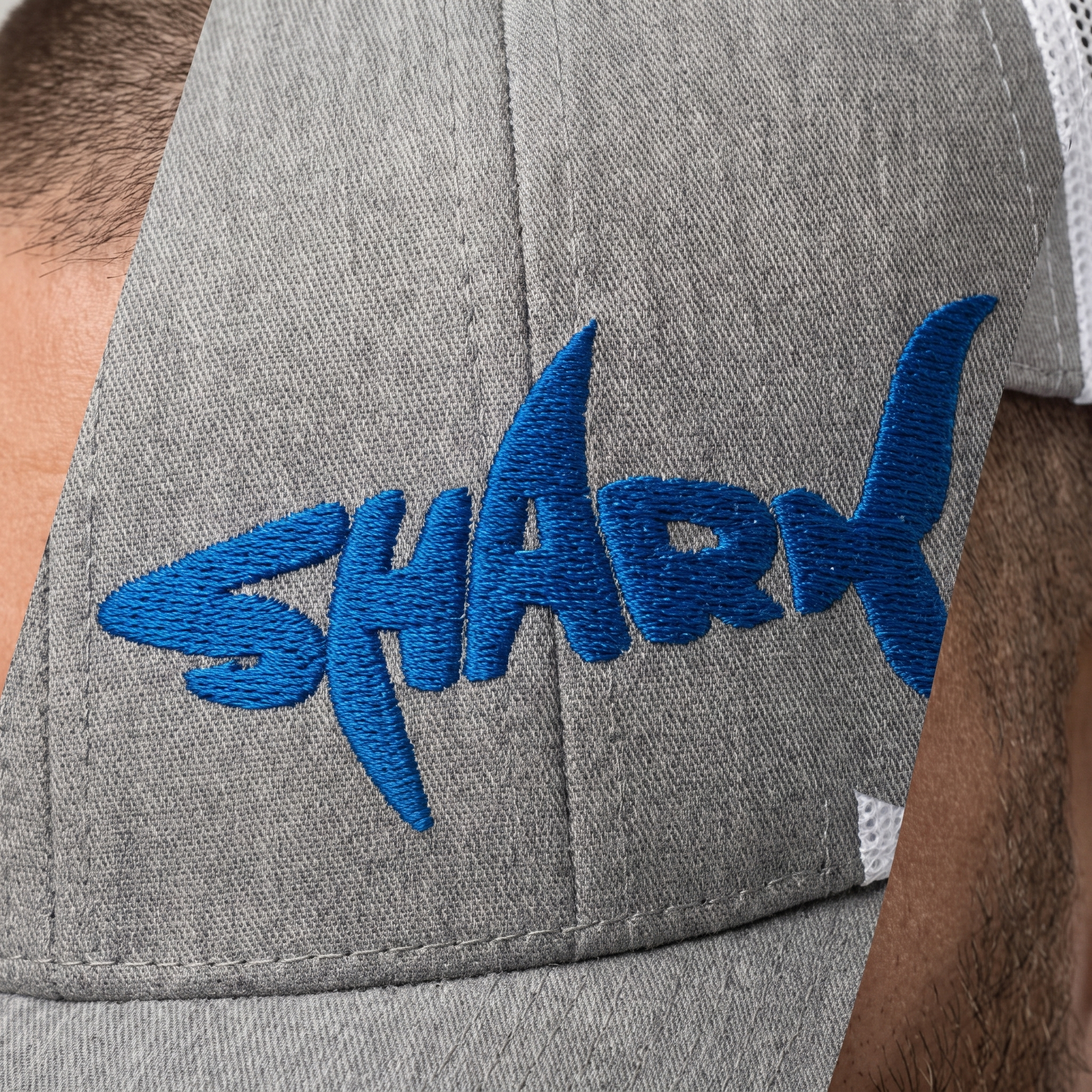 Gros plan du design requin SHARK brodé bleu roi sur le panneau avant de la casquette portée
