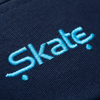 Macro de la broderie Skate bleu ciel sur le coton bleu marine de la casquette