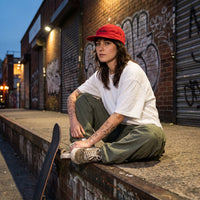 Casquette skate 5 panneaux rouge portée par une skateuse en ville