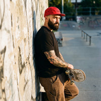 Casquette skate rouge portée par un skateur dans un skatepark urbain