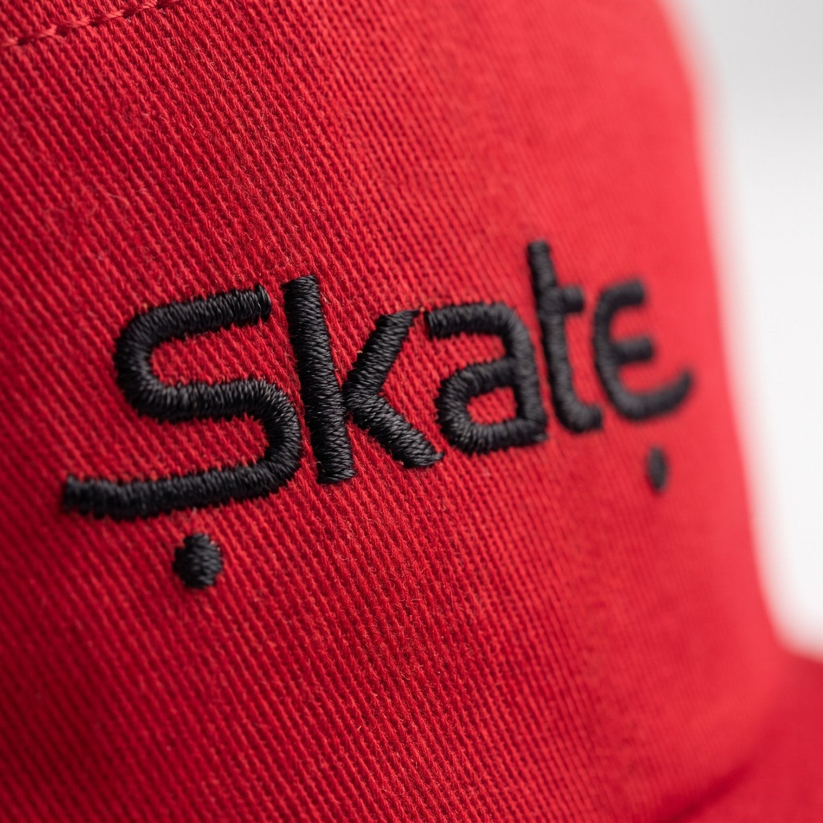 Macro de la broderie Skate noire sur le coton rouge de la casquette