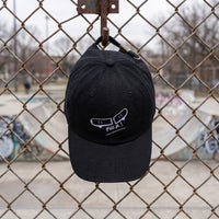 Casquette skate brodée FVCK noire suspendue à un grillage de skatepark, dad hat coton