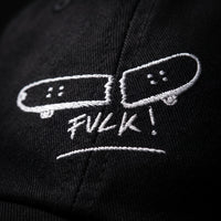 Macro de la broderie blanche skateboard cassé FVCK sur sergé de coton noir