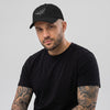 Homme portant la casquette skate brodée FVCK noire, dad hat streetwear à broderie skateboard cassé