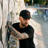 Homme skateur portant la casquette skate noire en rue, ambiance streetwear urbain