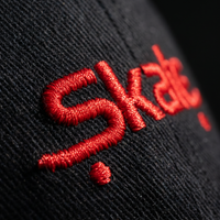 Macro de la broderie fil rouge Skate sur le coton chino noir de la casquette