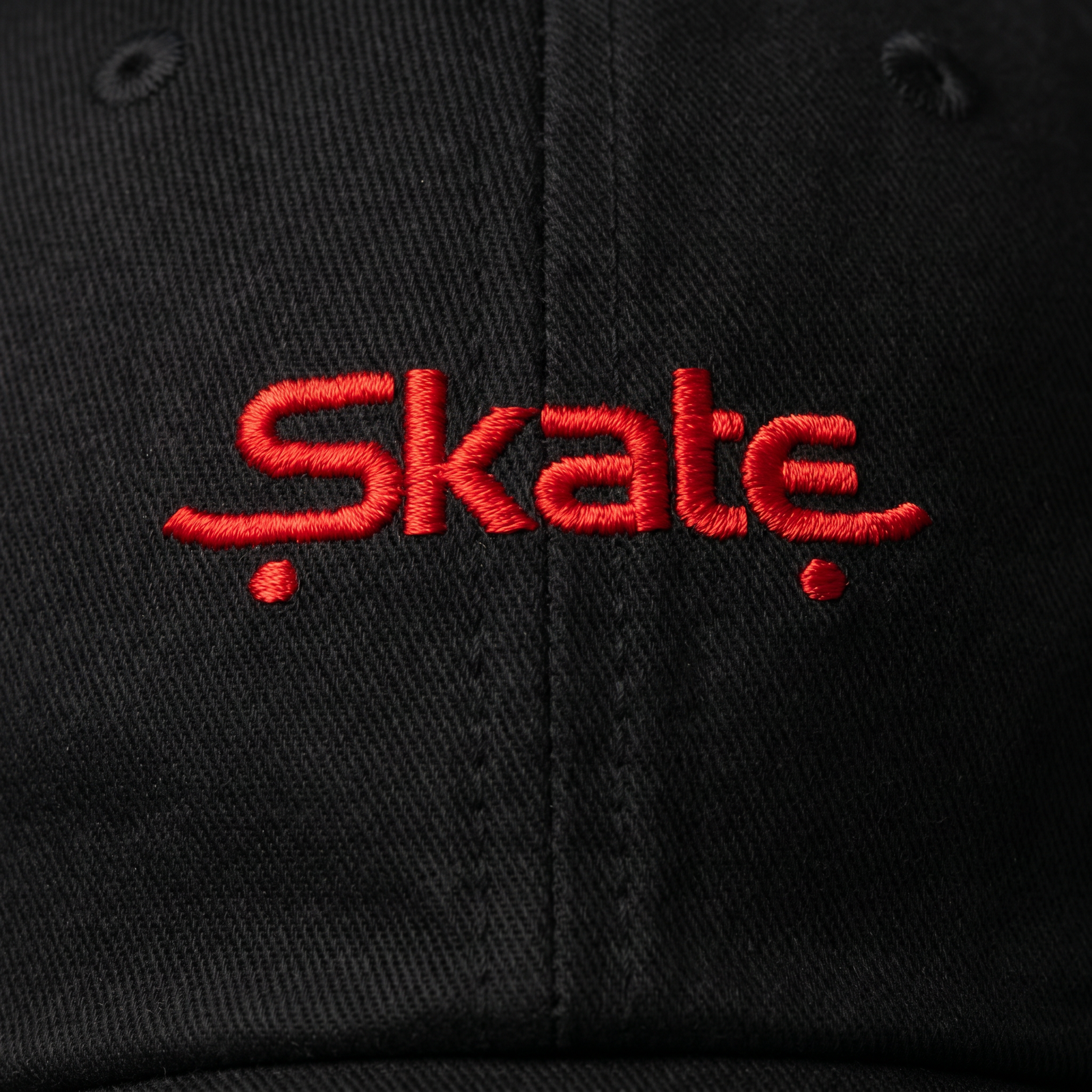 Zoom sur la broderie rouge Skate de la casquette noire portée, détail du design