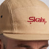 Gros plan sur la broderie rouge Skate de la casquette 5 panneaux beige portée