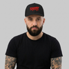 Homme portant la casquette skate trucker noire à broderie crocodile rouge, photo studio