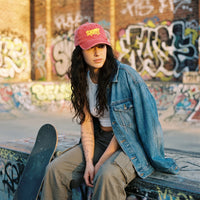 Femme skateuse en rue urbaine portant la casquette skate vintage rouge originale brodée