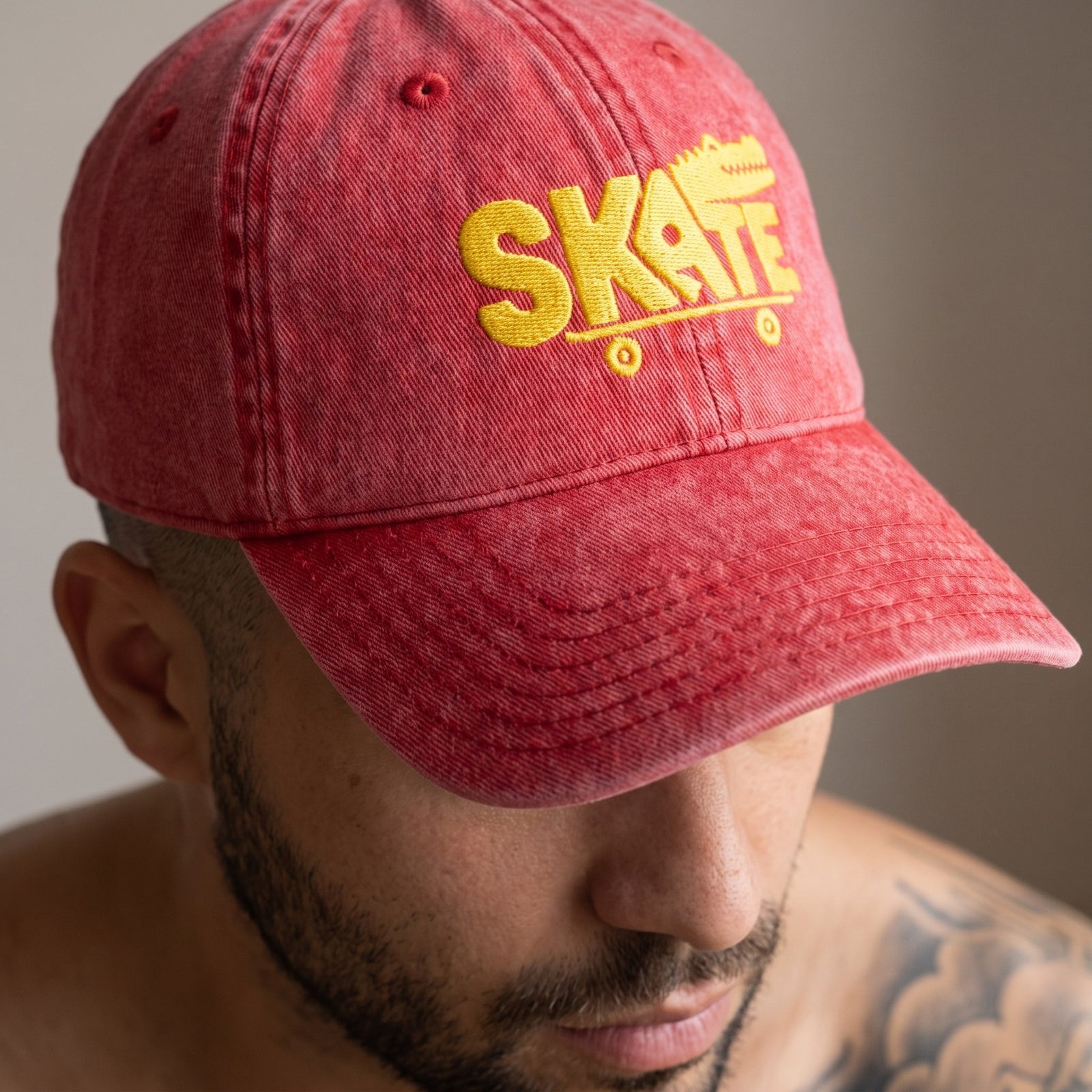Gros plan sur la broderie SKATE crocodile jaune de la casquette vintage rouge portée