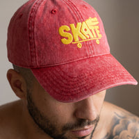 Gros plan sur la broderie SKATE crocodile jaune de la casquette vintage rouge portée
