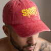 Gros plan sur la broderie SKATE crocodile jaune de la casquette vintage rouge portée