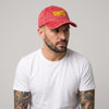 Casquette skate vintage rouge délavé brodée crocodile portée par un homme en studio