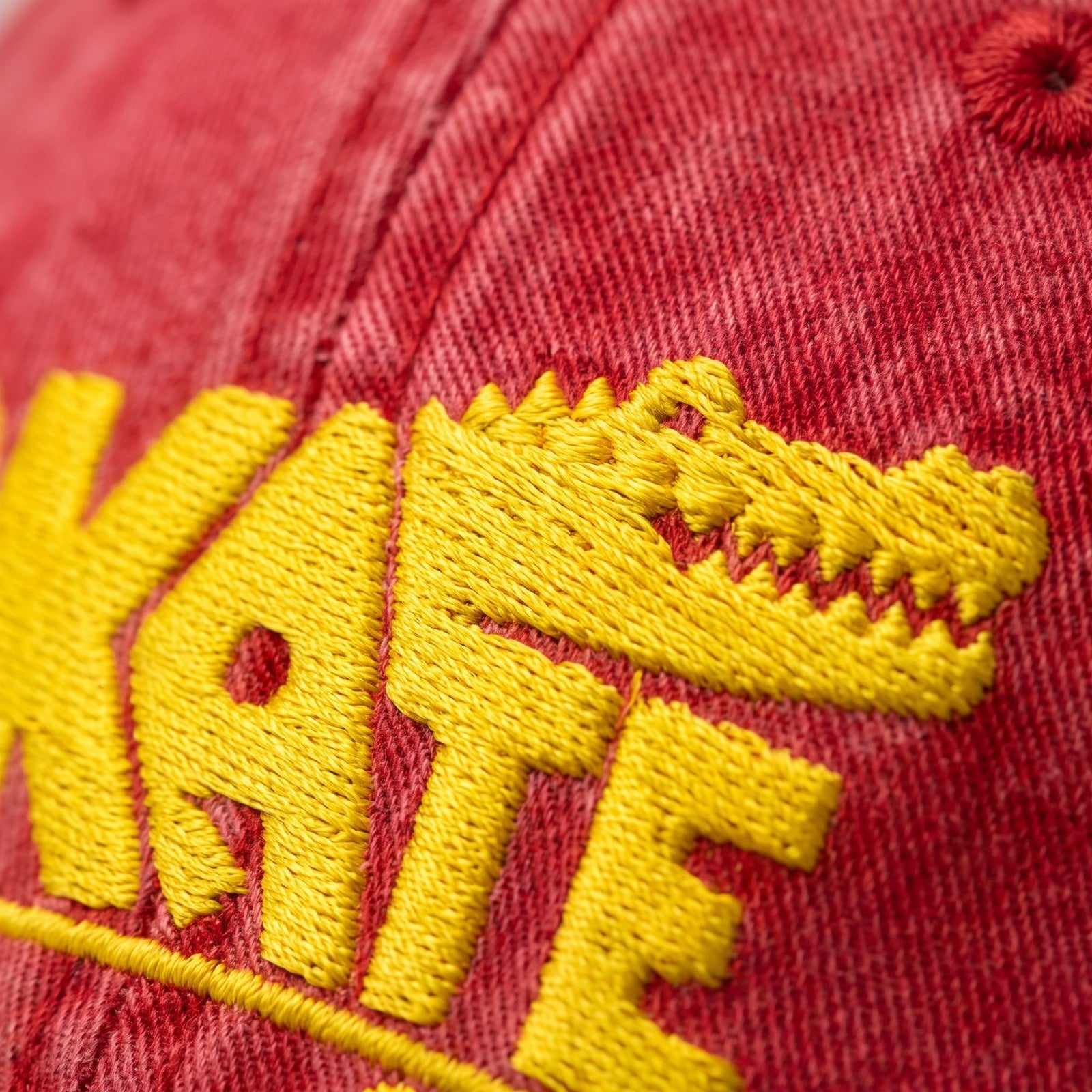 Macro de la broderie crocodile jaune fil à fil sur le sergé de coton rouge délavé