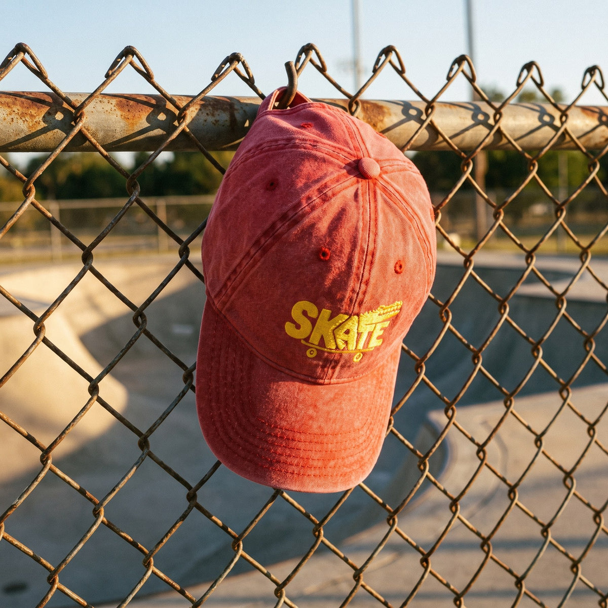 Casquette skate vintage rouge brodée crocodile accrochée au grillage d'un skatepark