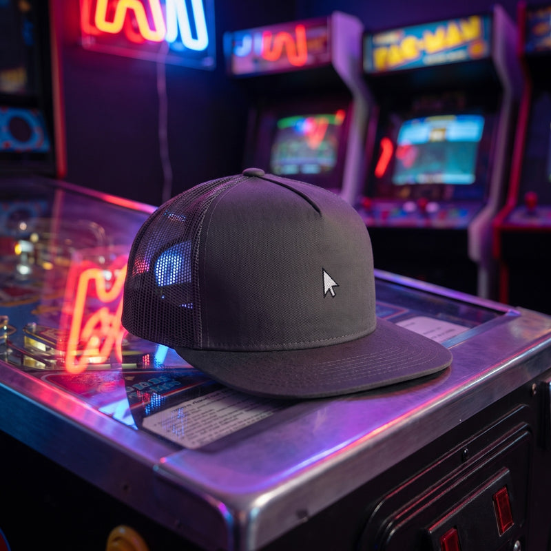 Casquette snapback gris anthracite à filet 5 panneaux brodée d'une petite flèche de souris blanche posée sur une borne d'arcade dans une salle de jeux rétro éclairée au néon - CHT'M Boutique