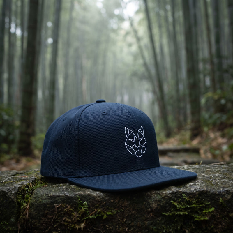 Casquette snapback bleu marine brodée d'une tête de tigre origami géométrique blanche posée sur une marche en pierre dans une forêt de bambous brumeuse - CHT'M Boutique