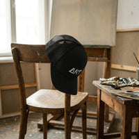Casquette ART noire posée dans un atelier d'artiste, ambiance créative - CHT'M Boutique