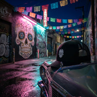 Ambiance streetwear nocturne casquette trucker calavera brodée blanche - ruelle graffiti neon tête de mort mexicaine CHT'M Boutique