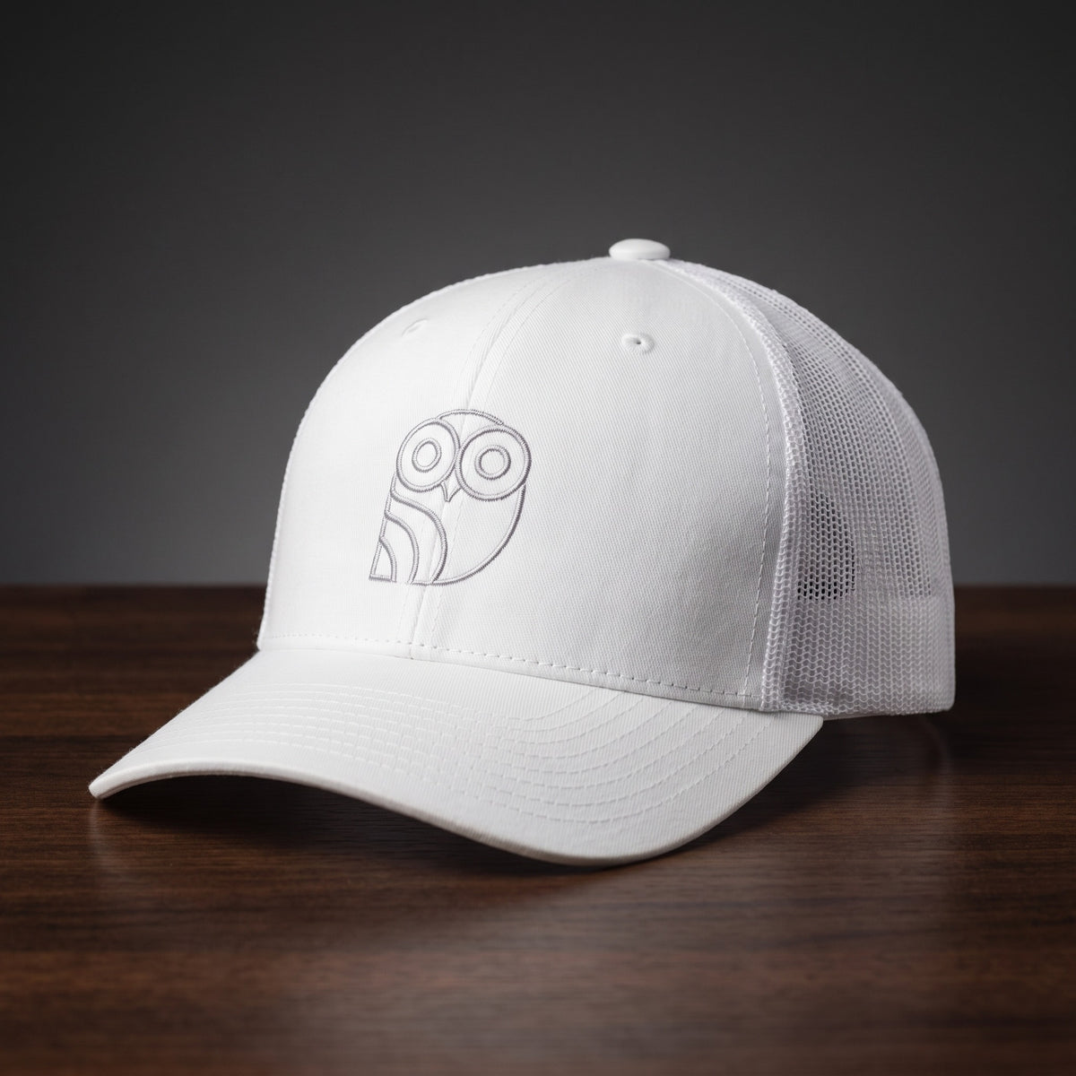 Casquette trucker brodée hibou Coolawls blanche, vue trois-quarts sur fond bois