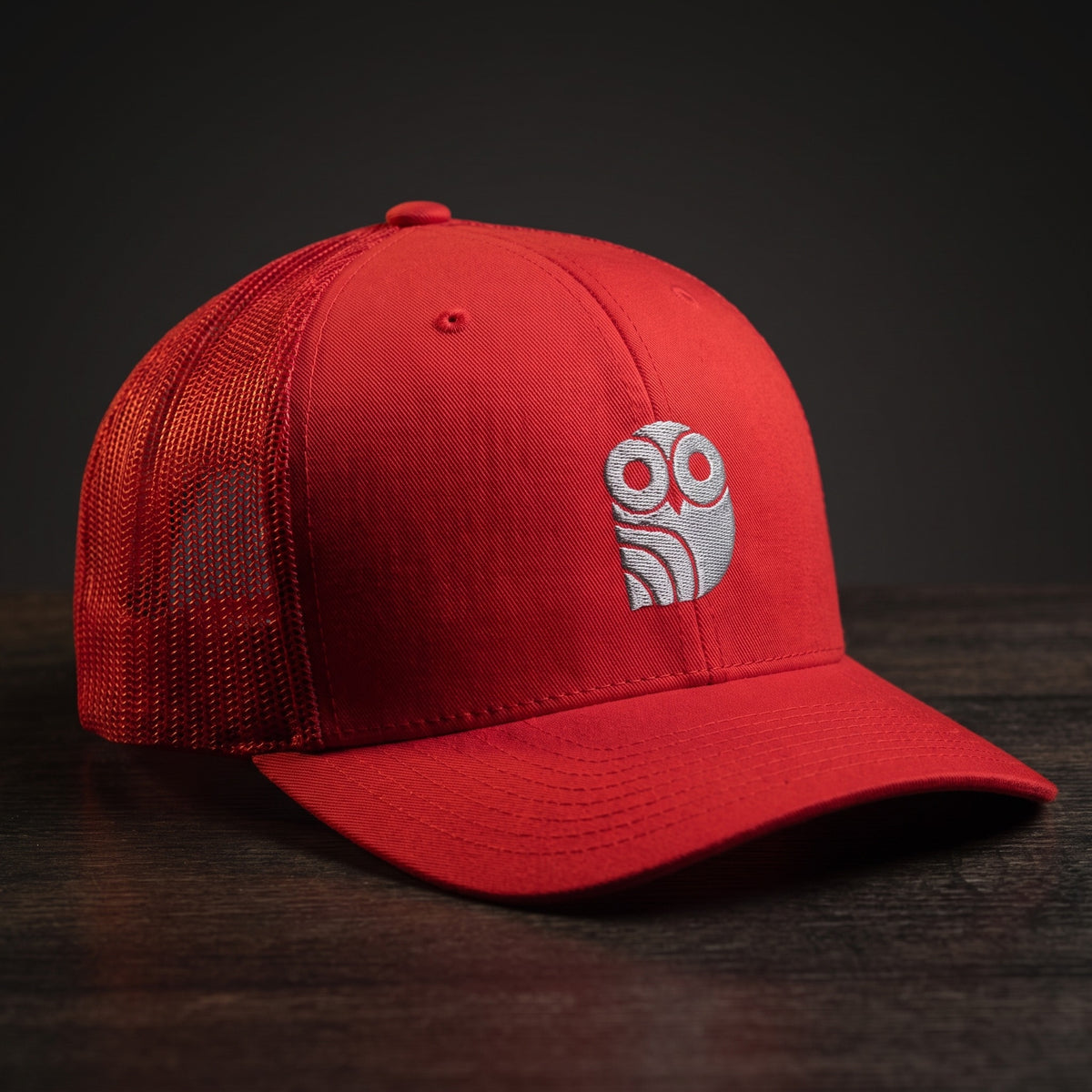 Casquette trucker brodée hibou Coolawls rouge, vue trois-quarts sur fond bois