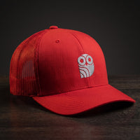 Casquette trucker brodée hibou Coolawls rouge, vue trois-quarts sur fond bois