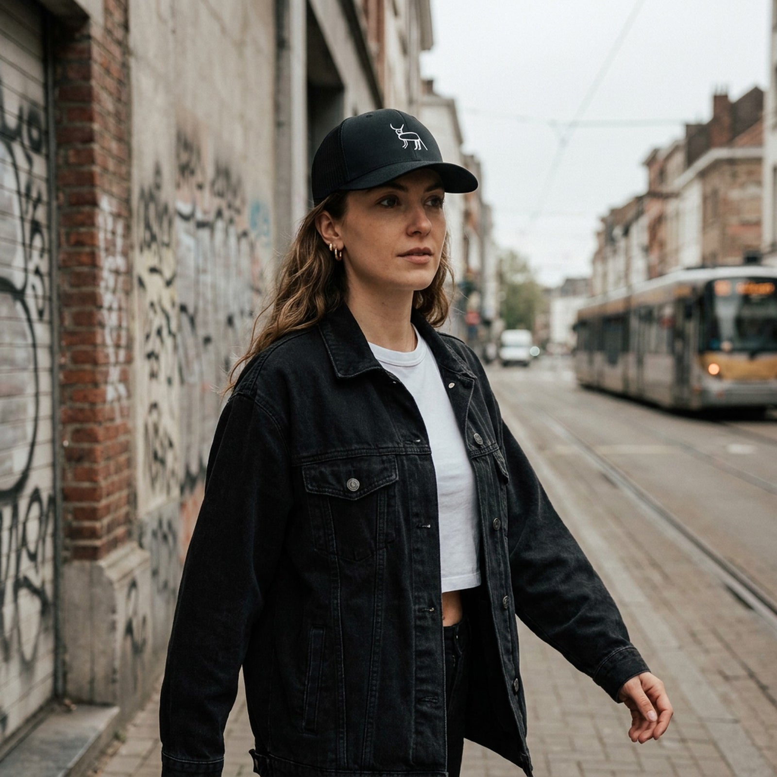Femme en streetwear portant la casquette originale Coucou Petite Perruche dans une rue de Bruxelles